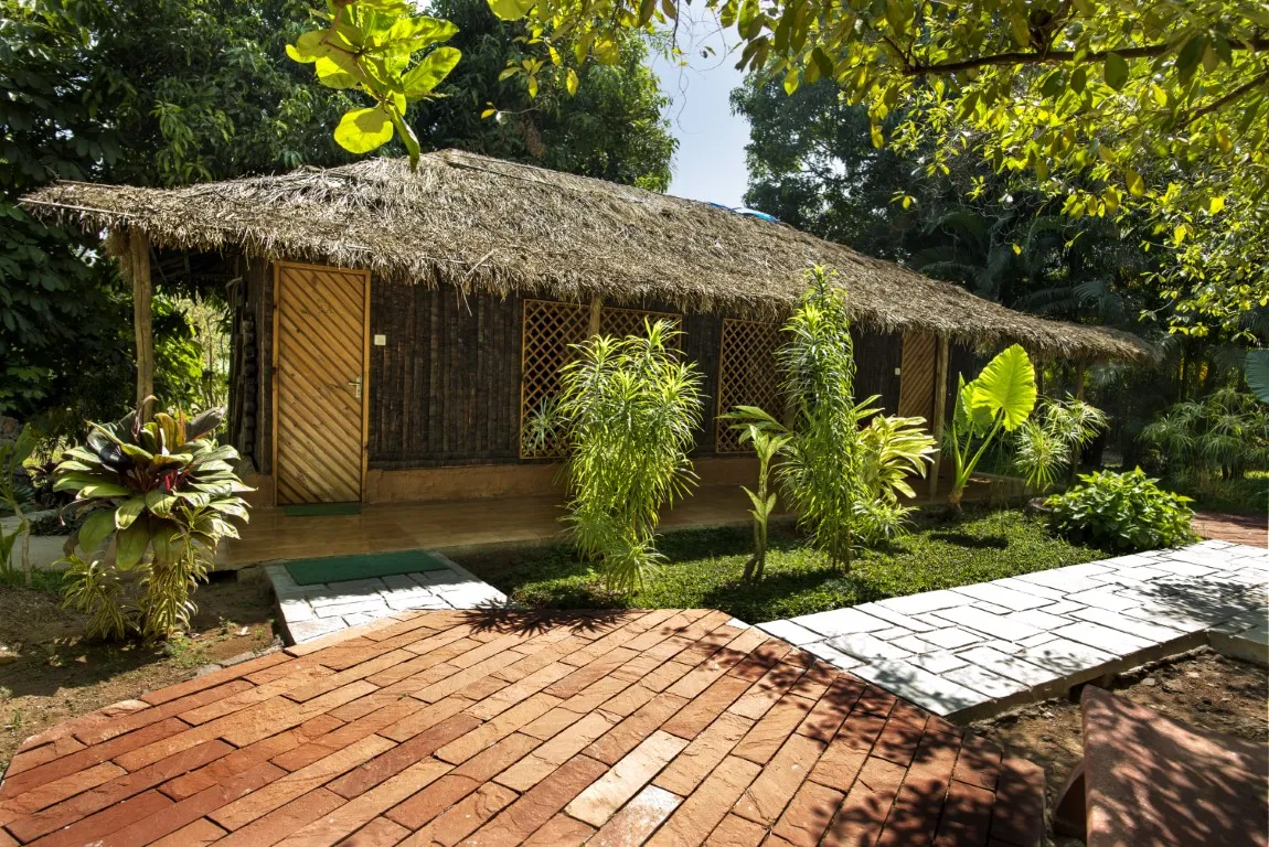 Coconut Log House couple accommodation with traditional thatched roof at Save Farm